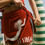 Woman wearing Le Sirenuse wrap towel skirt, mid-tie. 