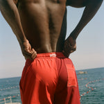 Man wearing red Le Sirenuse swim shorts.
