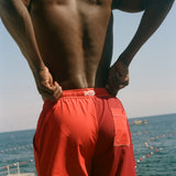 Man wearing red Le Sirenuse swim shorts.