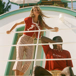 Two people standing by a scenic ocean view, wearing shirts from the Le Sirenuse x Tombolo collaboration.