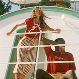 Two people standing by a scenic ocean view, wearing shirts from the Le Sirenuse x Tombolo collaboration.