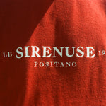 Red garment with 'Le Sirenuse Positano' branding on a blurred background
