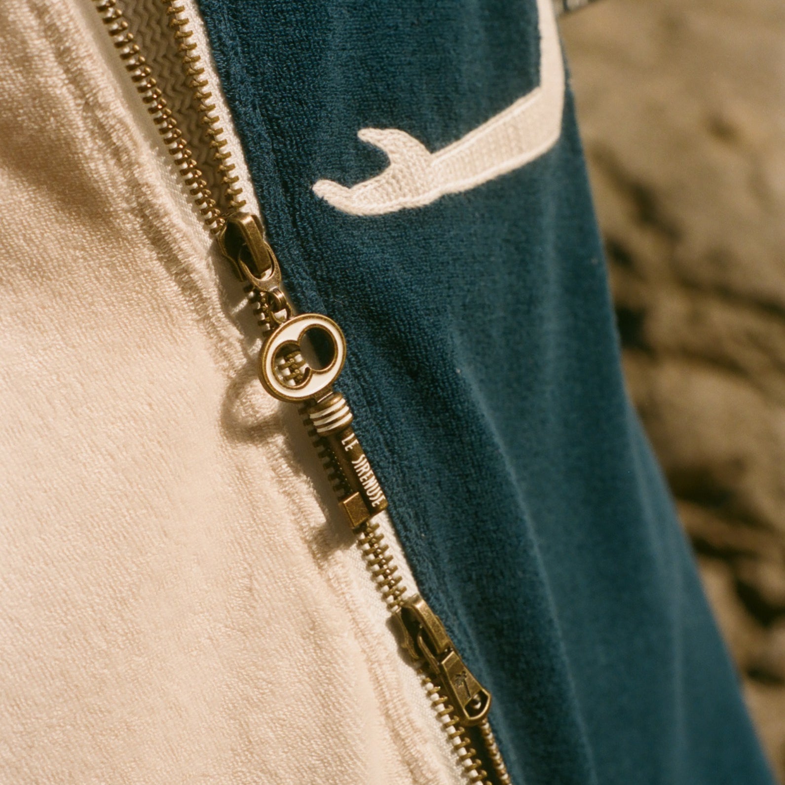 Close-up of a key zipper on a garment with a blue and beige pattern.