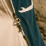 Close-up of a key zipper on a garment with a blue and beige pattern.