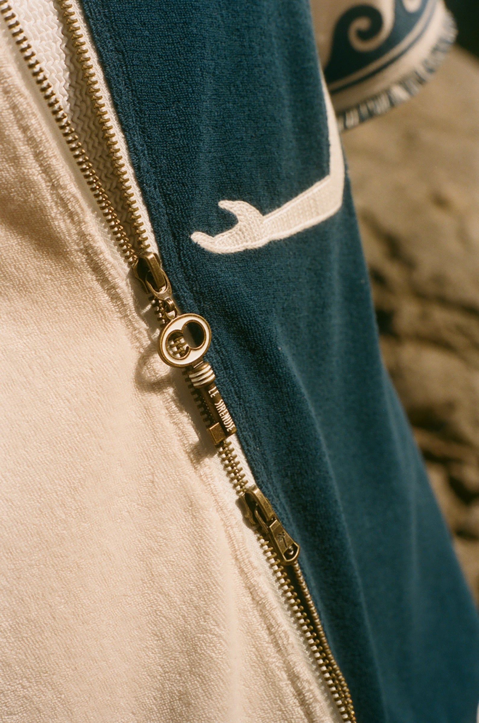 Close-up of a key zipper on a garment with a blue and beige pattern.