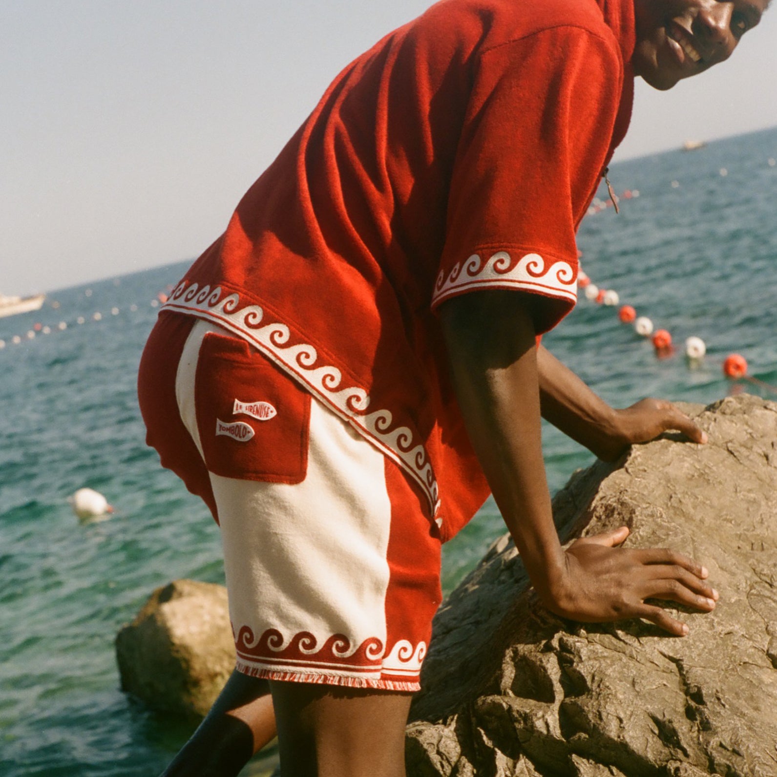Man climbing on a rock, wearing the Le Sirenuse Beach Towel top. 