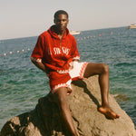 Man wearing Le Sirenuse Beach Towel top and matching red terry cloth shorts. 