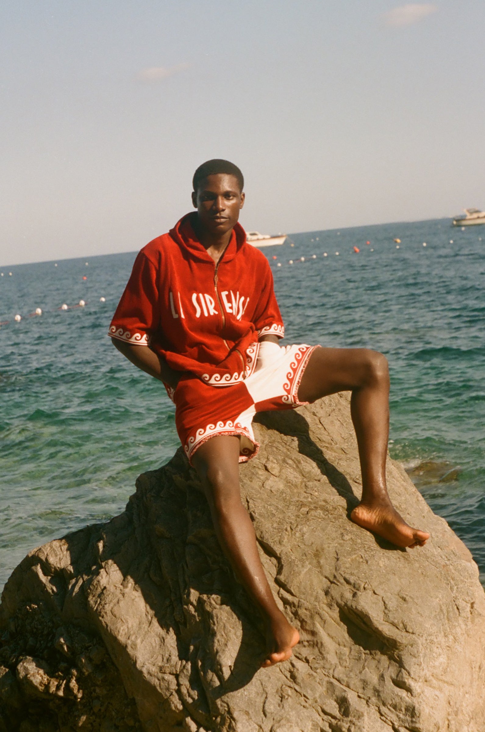 Man wearing Le Sirenuse Beach Towel top and matching red terry cloth shorts. 