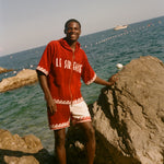 Man wearing Le Sirenuse Beach Towel top and matching red terry cloth shorts. 