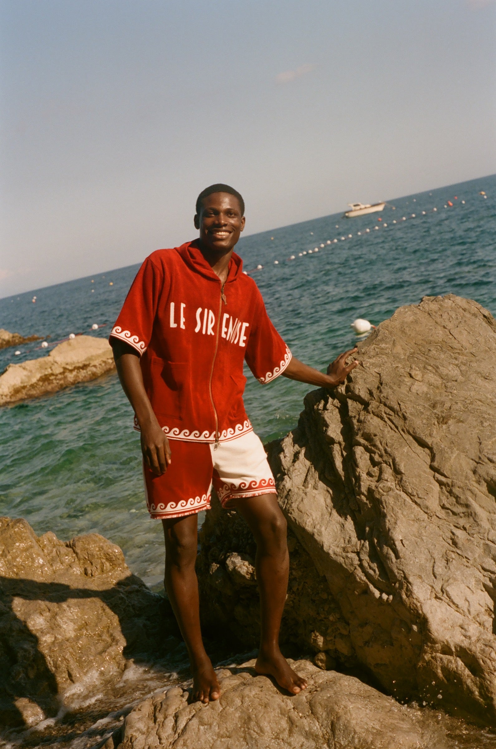 Man wearing Le Sirenuse Beach Towel top and matching red terry cloth shorts. 