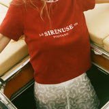 Person wearing a red 'Le Sirenuse Positano' t-shirt on a boat.