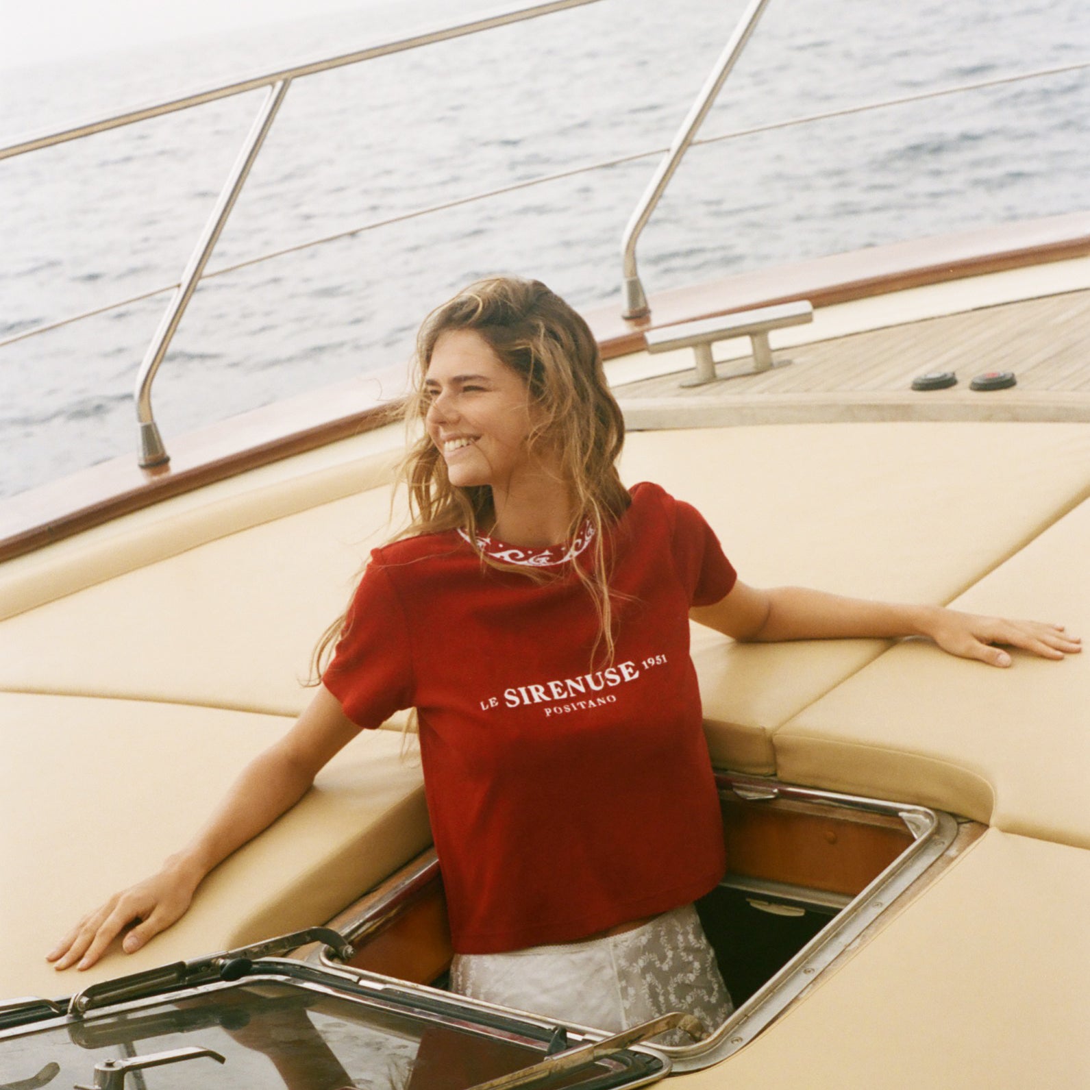 Woman in a red Le Sirenuse shirt on a boat 