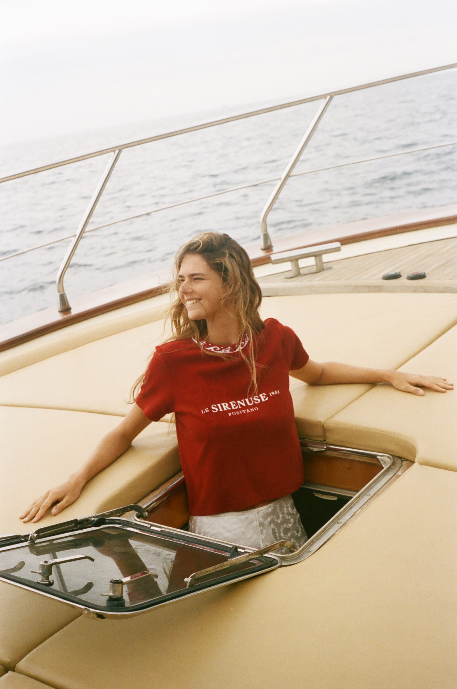 Woman in a red Le Sirenuse shirt on a boat 