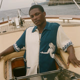 Man wearing Blue and beige Le Sirenuse Late Checkout Cabana, sitting on a boat. 