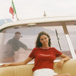 Woman in a red shirt sitting on a boat with an Italian flag in the background