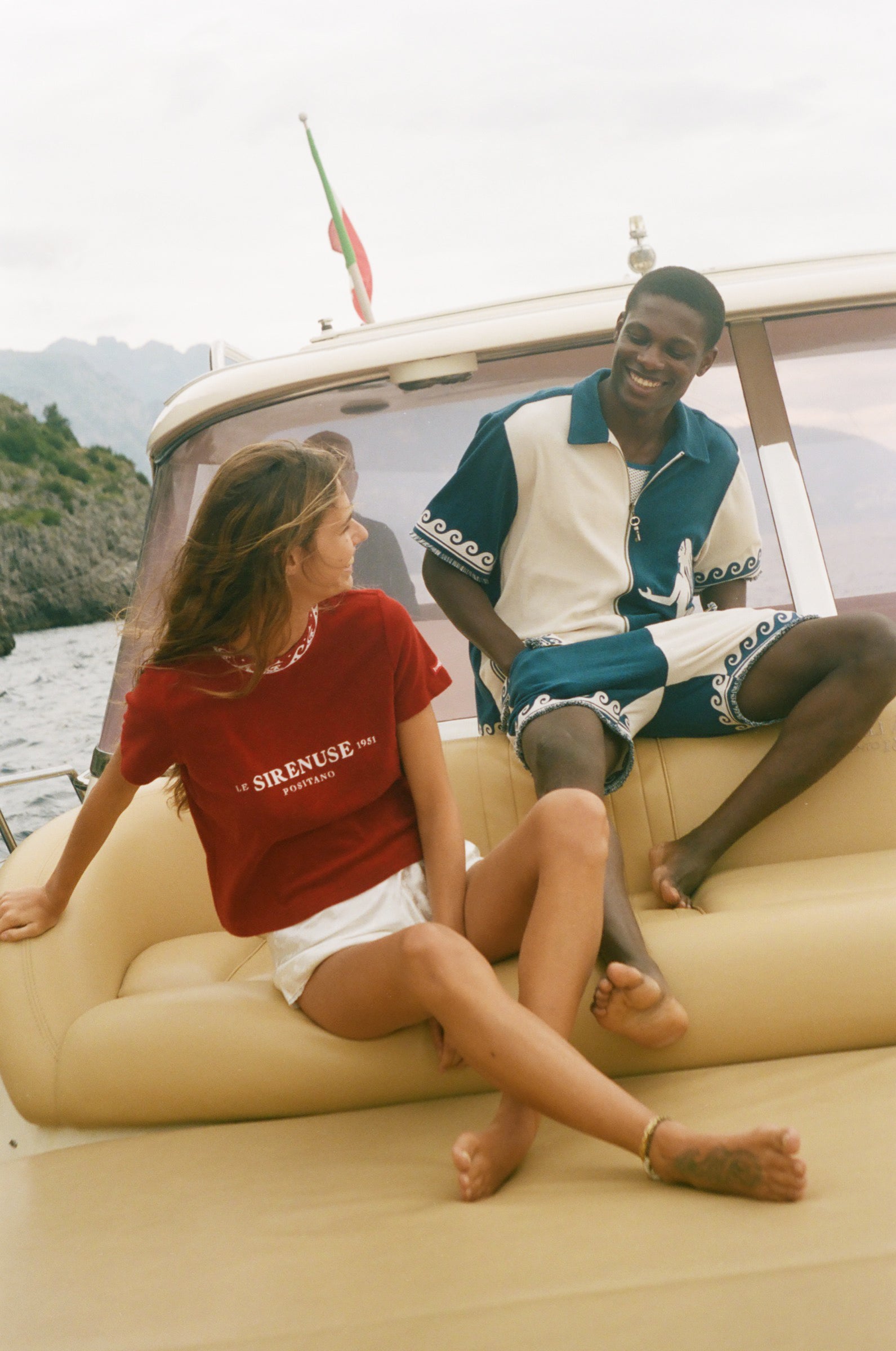 Two people sitting on a boat with scenic background.