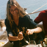 Woman enjoying a meal by the sea with a scenic background