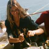 Woman enjoying a meal by the sea with a scenic background