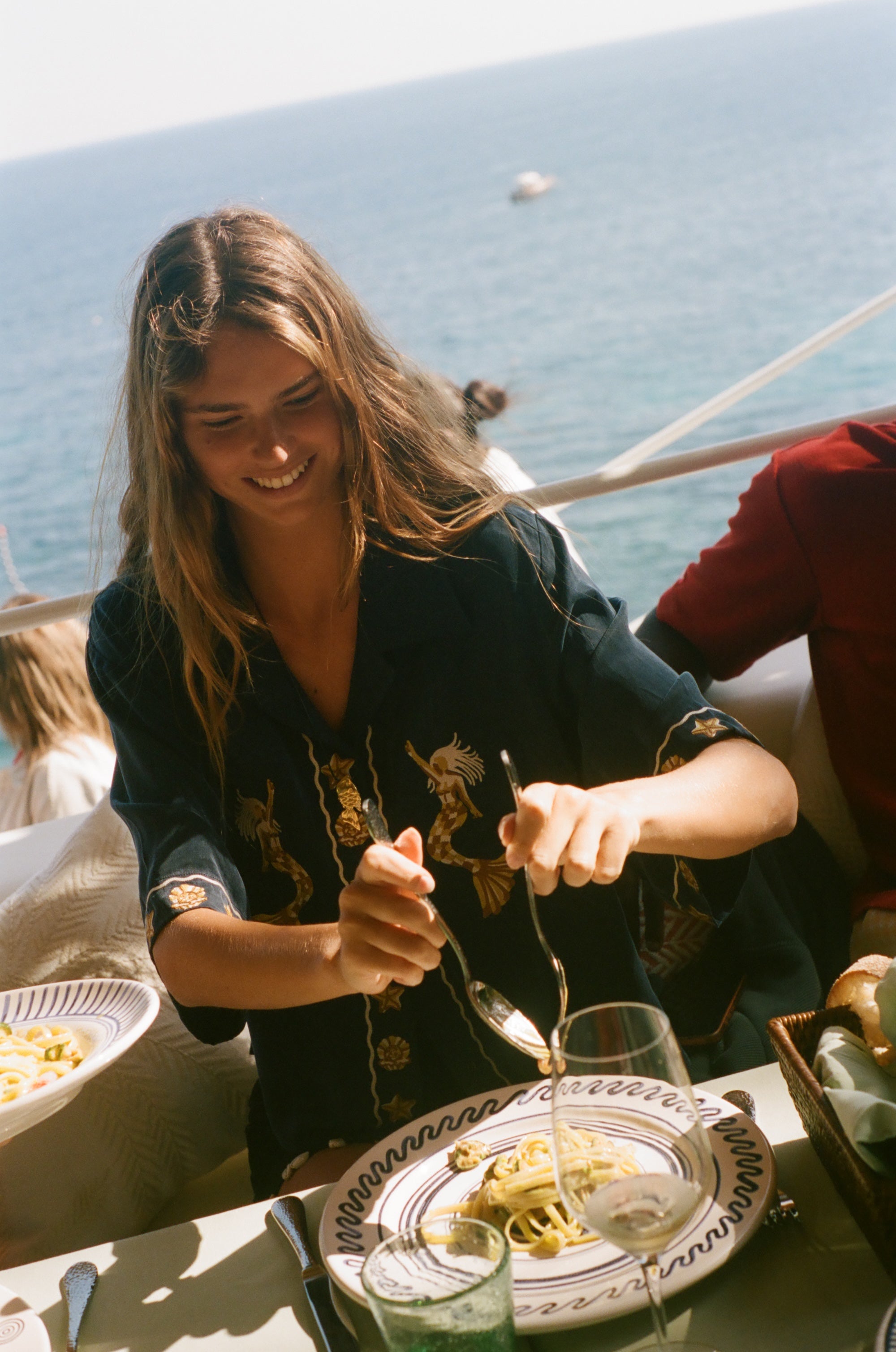 Woman enjoying a meal by the sea with a scenic background