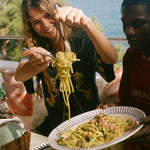 Woman eating noodles outdoors, wearing the Le Sirenuse 'Don't Worry' relaxed crop cut. 
