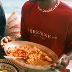 Person holding a plate of pasta with a scenic background