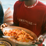 Person holding a plate of pasta with a scenic background