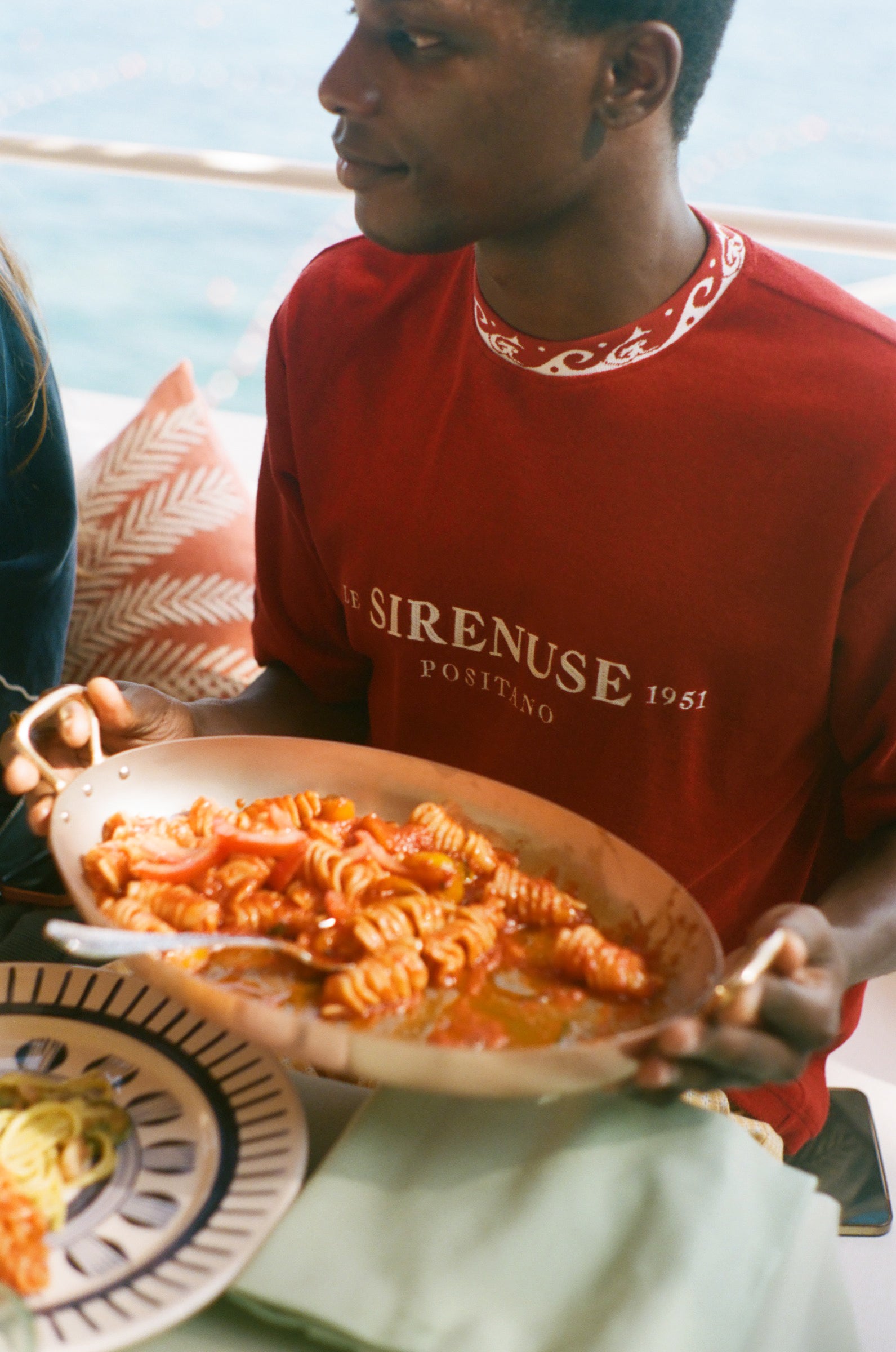 Person holding a plate of pasta with a scenic background