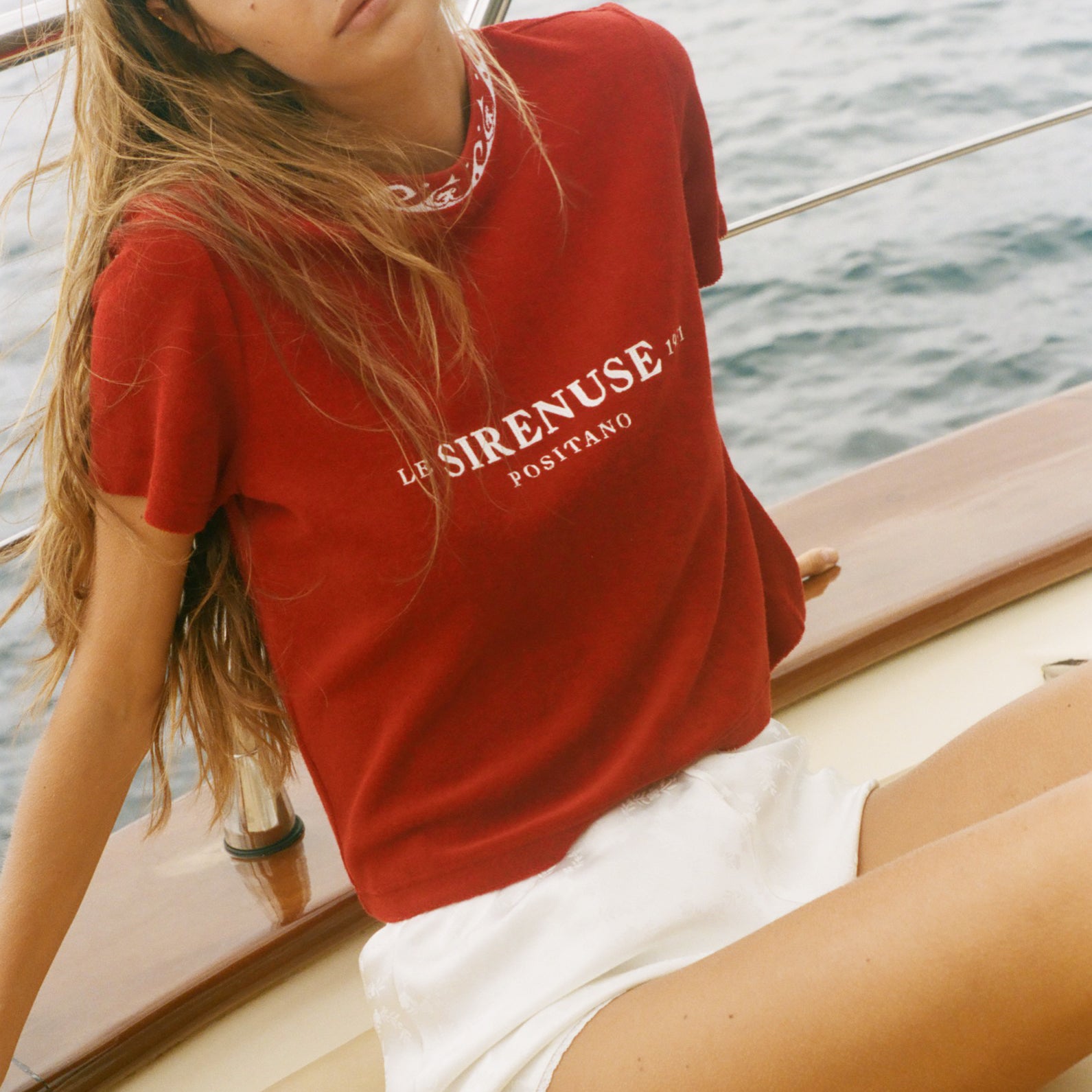 Woman wearing a red t-shirt with 'SIRENUSE' branding on a boat.