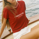 Woman wearing a red t-shirt with 'SIRENUSE' branding on a boat.