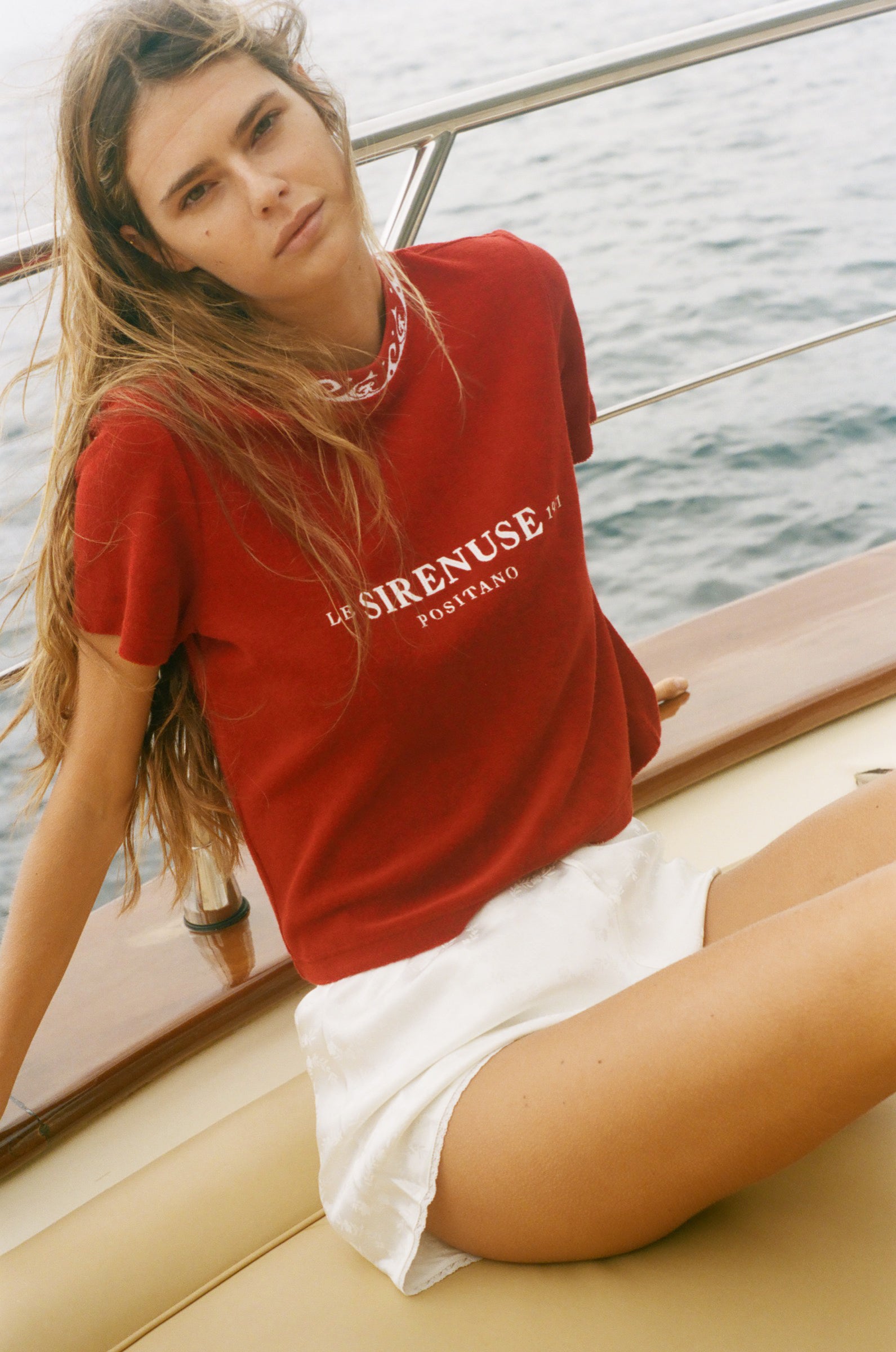 Woman wearing a red t-shirt with 'SIRENUSE' branding on a boat.