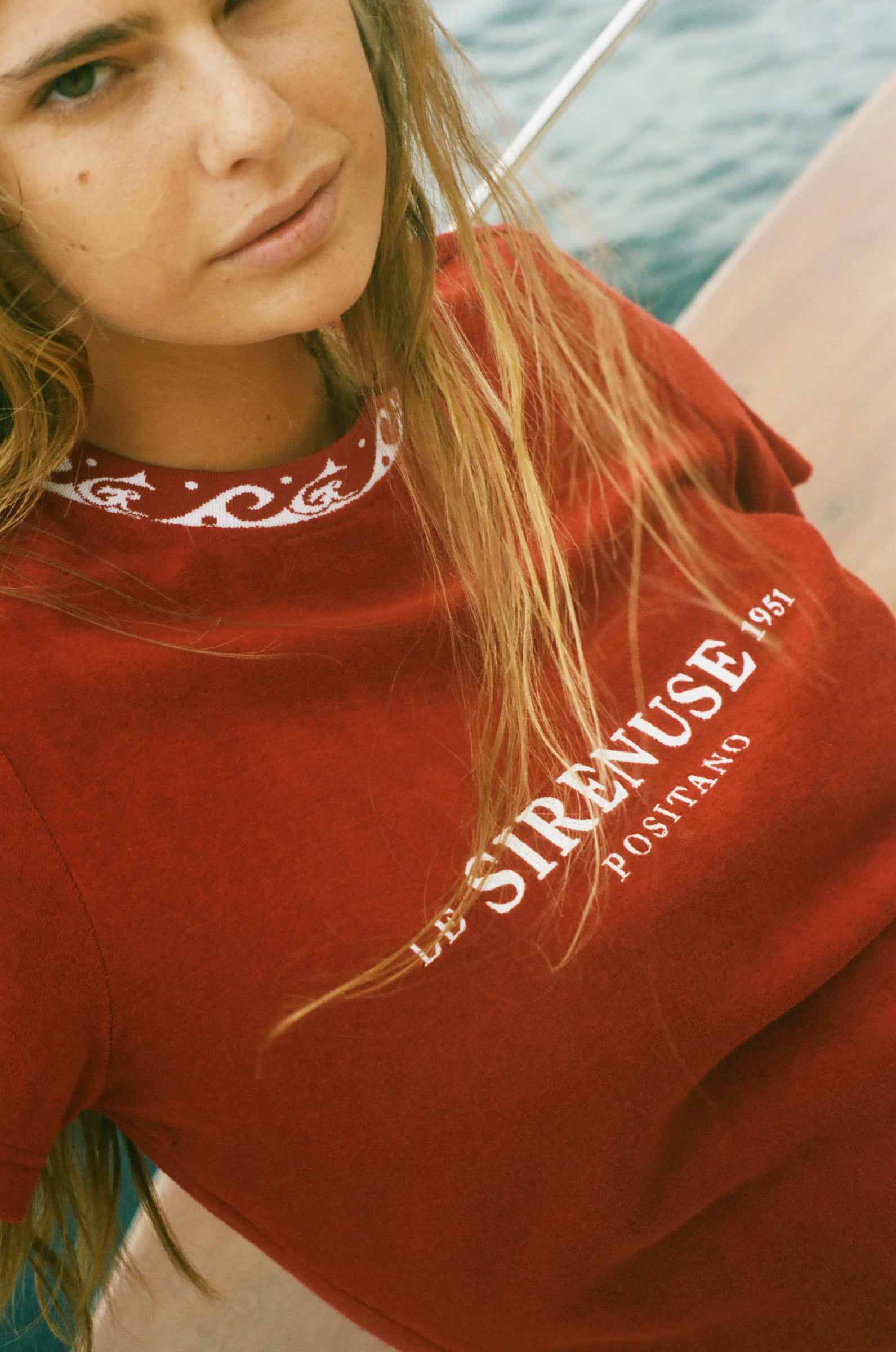 Close-up of woman wearing Le Sirenuse tee sitting on a boat.