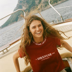 Woman in a red 'Sirenuse' t-shirt on a boat with a mountainous background