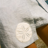Close cropped image of a light blue skirt featuring an appliquéd sand dollar.