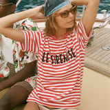 Woman in a red and white striped shirt with 'Le Sirenuse' embroidery on a boat