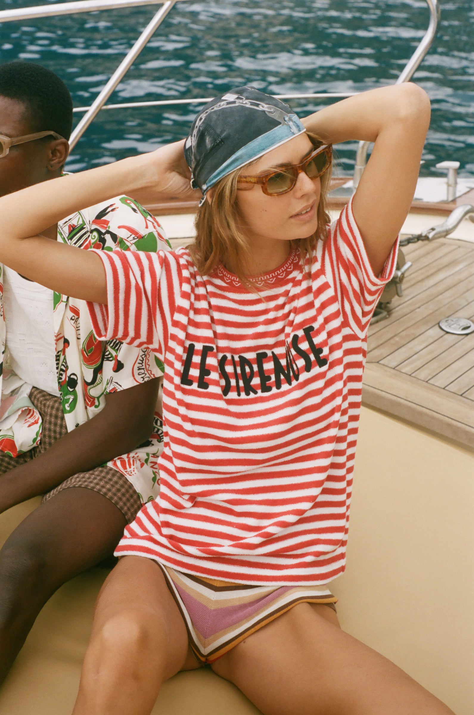 Woman in a red and white striped shirt with 'Le Sirenuse' embroidery on a boat