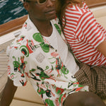 Two people standing close together, one wearing a colorful patterned shirt and sunglasses, the other in a red and white striped shirt.