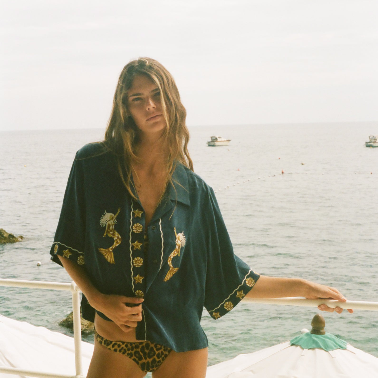 Woman standing on a boat with ocean in the background, wearing relaxed crop cut Don't Worry shirt.