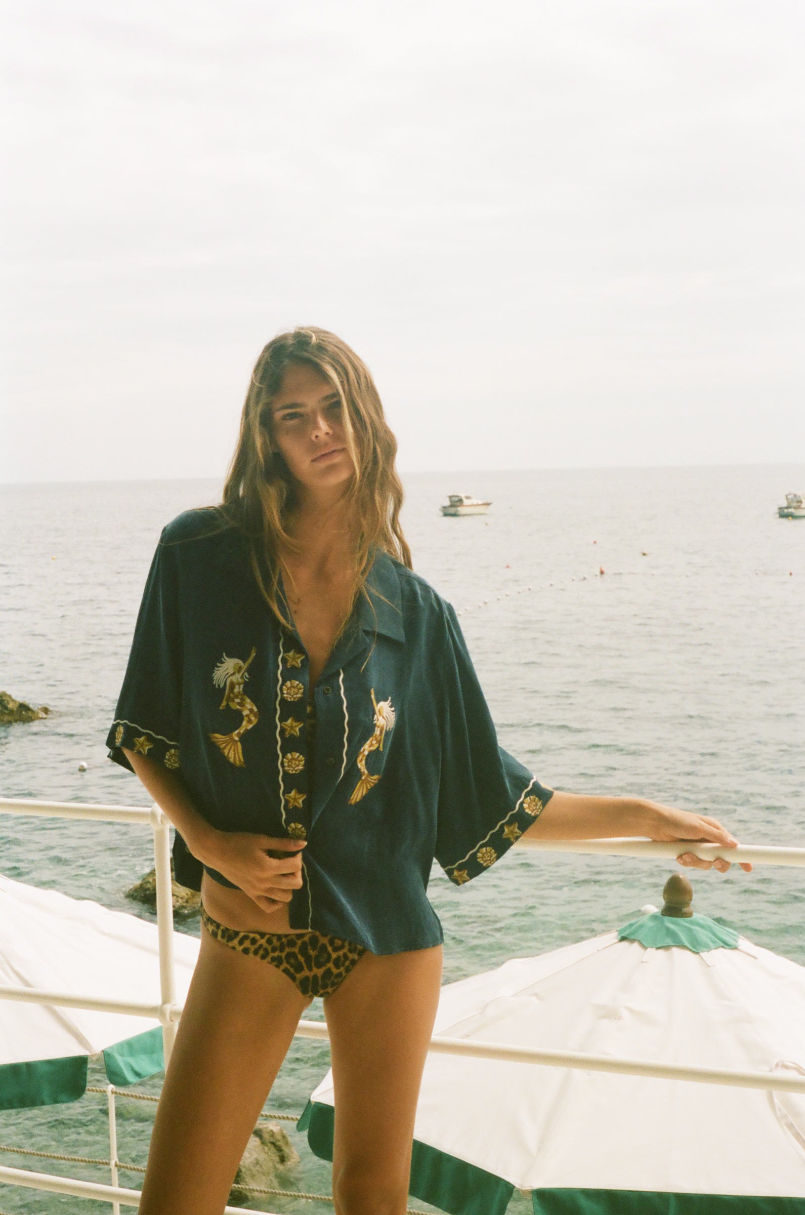 Woman standing on a boat with ocean in the background, wearing relaxed crop cut Don't Worry shirt.