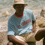 Person wearing a striped shirt and hat by the water