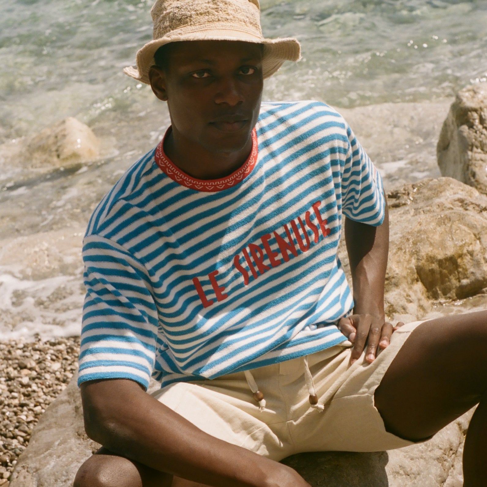 Person wearing a striped shirt and hat by the water