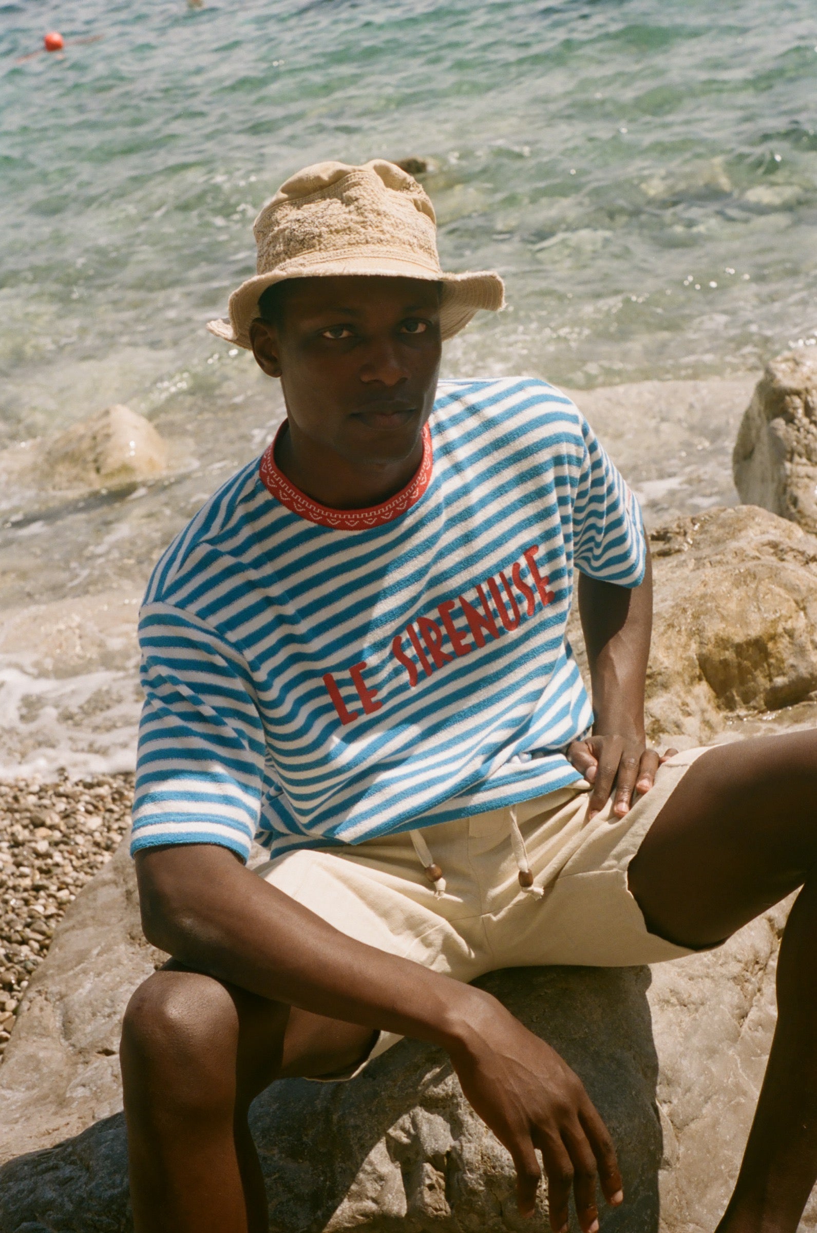Person wearing a striped shirt and hat by the water