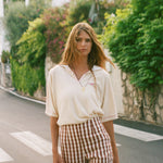 Woman wearing the Le Sirenuse beige polo shirt and checkered pants. 