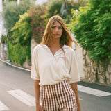 Woman wearing the Le Sirenuse beige polo shirt and checkered pants. 
