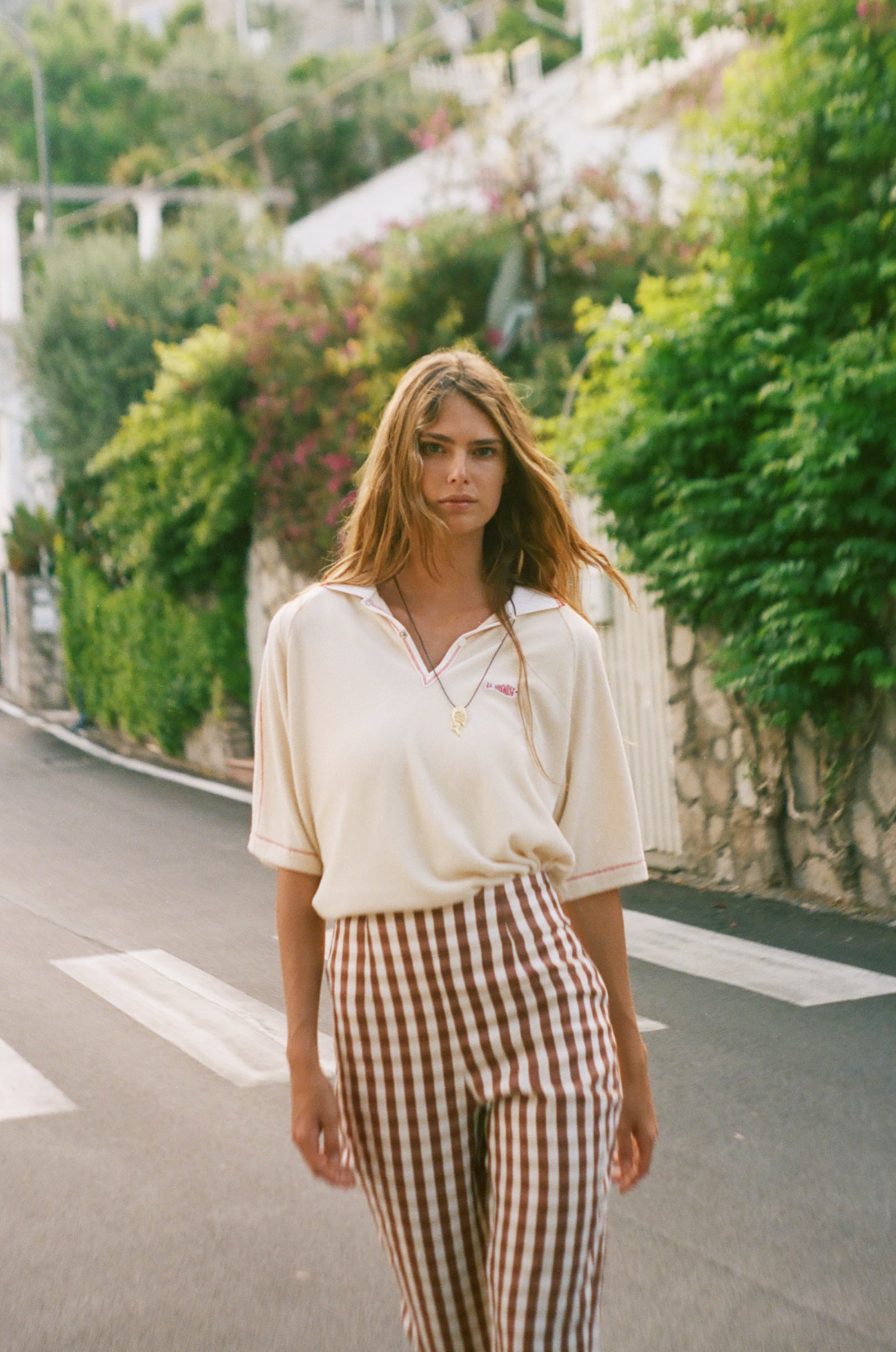 Woman wearing the Le Sirenuse beige polo shirt and checkered pants. 