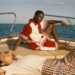 Two people on a boat with one person lying down and the other sitting, wearing the Le Sirenuse x Tombolo collection.