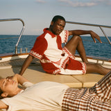 Two people on a boat with one person lying down and the other sitting, wearing the Le Sirenuse x Tombolo collection.