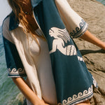 Woman wearing Le Sirenuse Late Checkout cabana shirt over a white swimsuit.