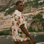 Man wearing a colorful shirt and sunglasses with a scenic coastal background