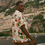 Man wearing a colorful shirt and sunglasses with a scenic coastal background