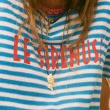 Person wearing a blue and white striped shirt with 'LE SIRENUSE' text, accessorized with necklaces.